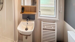 A bathroom with a white sink, wooden shelf, and a window with a view. - 3 bedroom accommodation in Sandgreen (Sandgreen)