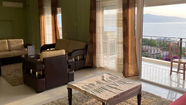 Un salon avec un canapé, une table basse et une vue sur la mer depuis un balcon.