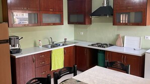 Une cuisine compacte avec des meubles en bois, une cuisinière à gaz, un évier et une machine à café.