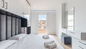 Een moderne slaapkamer met een groot bed, een kledingkast, een bureau en uitzicht.