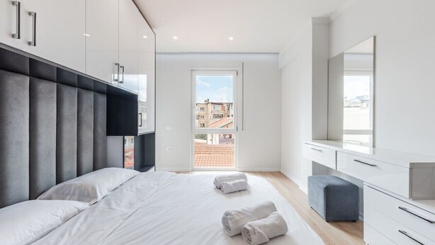 Un dormitorio moderno con una cama grande, un armario, un escritorio y vistas al exterior.
