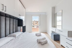 Une chambre moderne avec un grand lit, une armoire, un bureau et une vue sur l’extérieur.