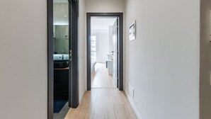 Un pasillo estrecho con suelo de madera que conduce a una habitación con un ventanal grande.