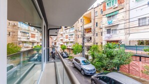 Una estrecha calle urbana con coches aparcados y edificios de varios pisos.