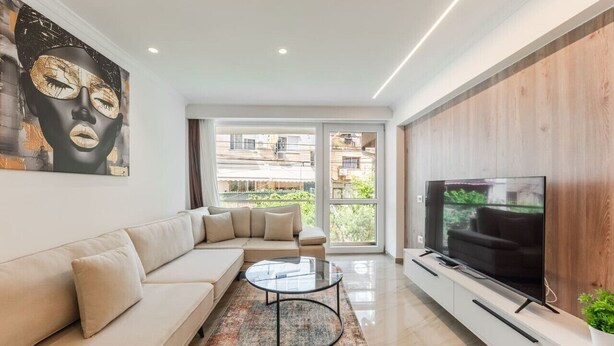 Una sala de estar moderna con sofá, mesa de centro, televisor y obras de arte.