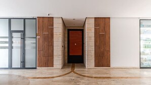 Un couloir avec une porte en bois, une porte en verre et un sol en marbre.