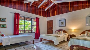 A room with two beds, a window with red curtains, wooden ceiling beams, and tiled flooring. - Fully Equipped Beach Bungalow 1 (Parrita)