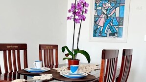 Un coin repas avec une table et des chaises en bois, une plante en pot et une œuvre d’art encadrée accrochée au mur.
