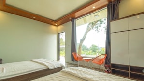 A hotel room with two beds, a large window with a view, and a seating area with orange chairs. - Coto Island Summer Hotel (Co To)