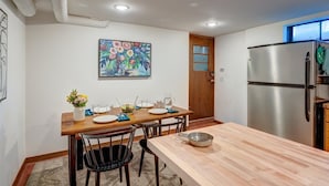 Een moderne keuken met een houten eettafel, stoelen en een roestvrijstalen koelkast.