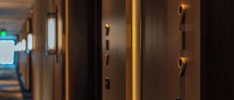 A hotel corridor with doors, a hallway, and a doorbell.