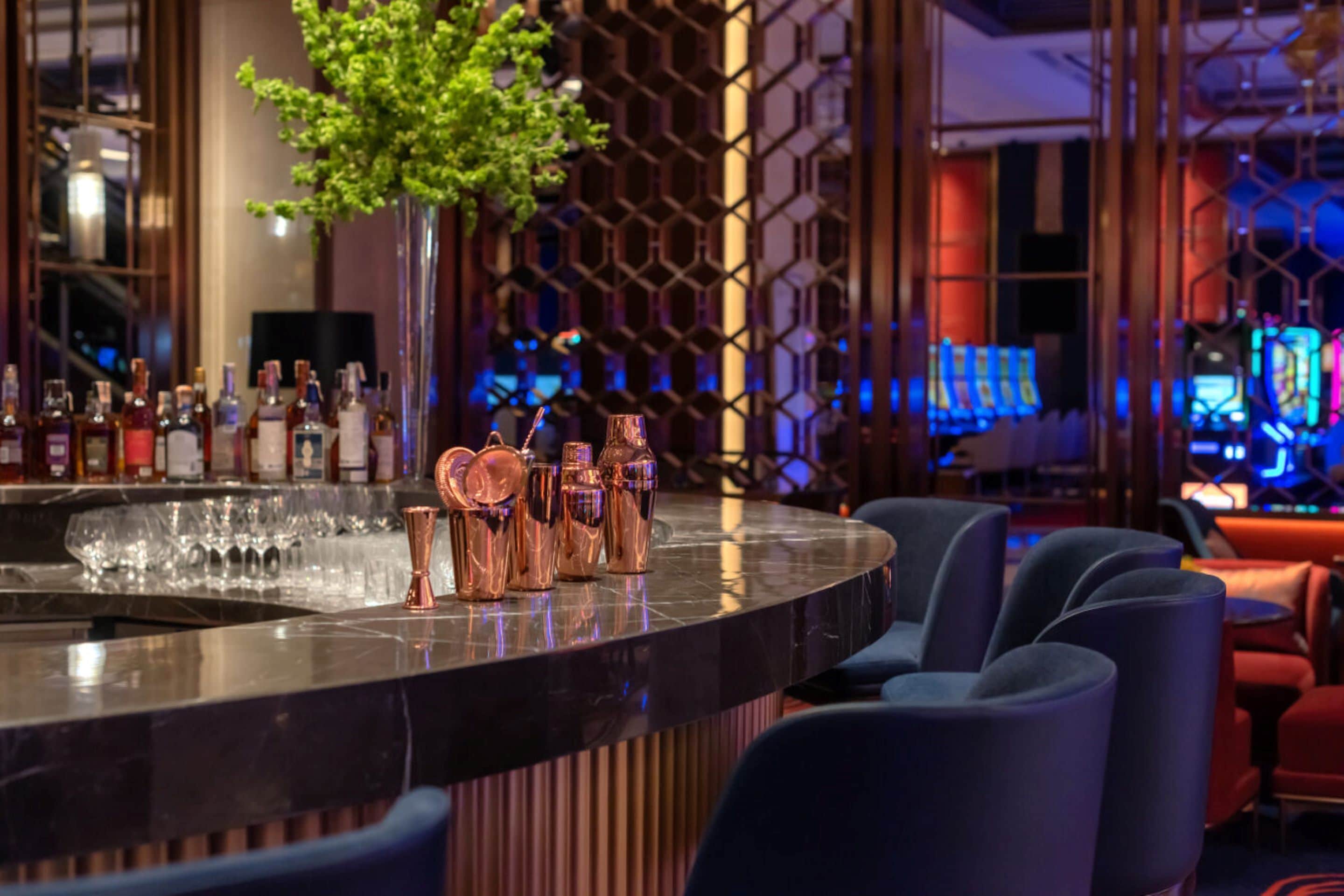 Una zona de bar con mostrador de mármol, utensilios de cobre y una planta en maceta.