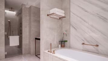 A modern bathroom with a marble wall, a bathtub, a towel rack, and a shower area.