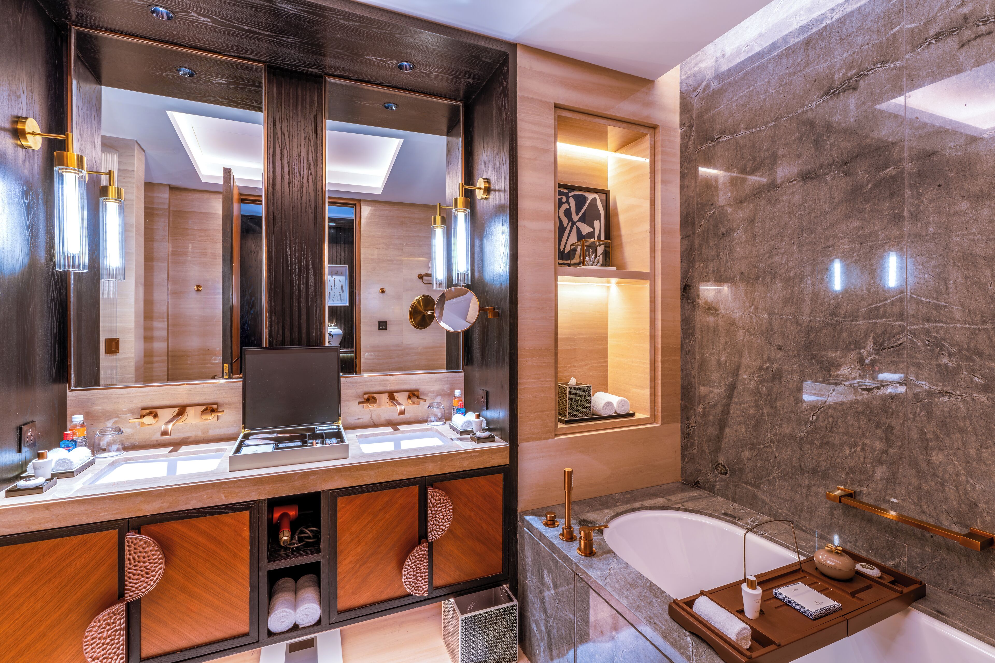 A modern bathroom with a large mirror, dual sinks, a bathtub, and a vanity with storage cabinets.