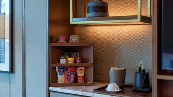 A kitchen counter with shelves holding various food items and a coffee machine.