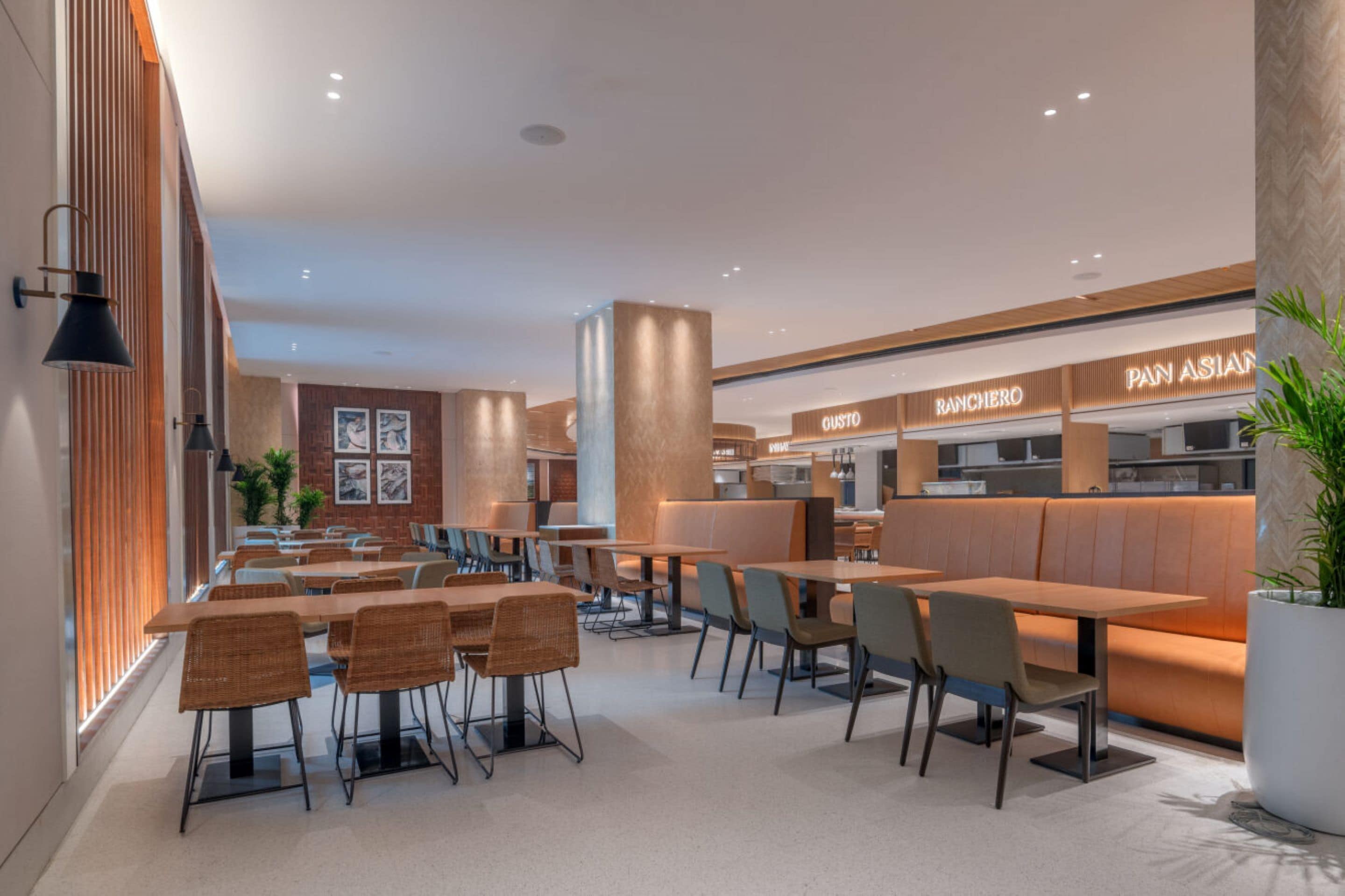 Ein modernes Restaurant mit Holztischen und -stühlen, einer Ziegelwand und einer Theke mit der Beschriftung 'PAN ASIAN'.