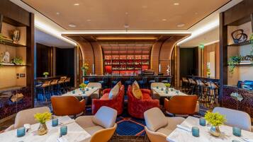 A modern bar area with seating and a bar counter, featuring a variety of seating arrangements and a well-stocked bar.