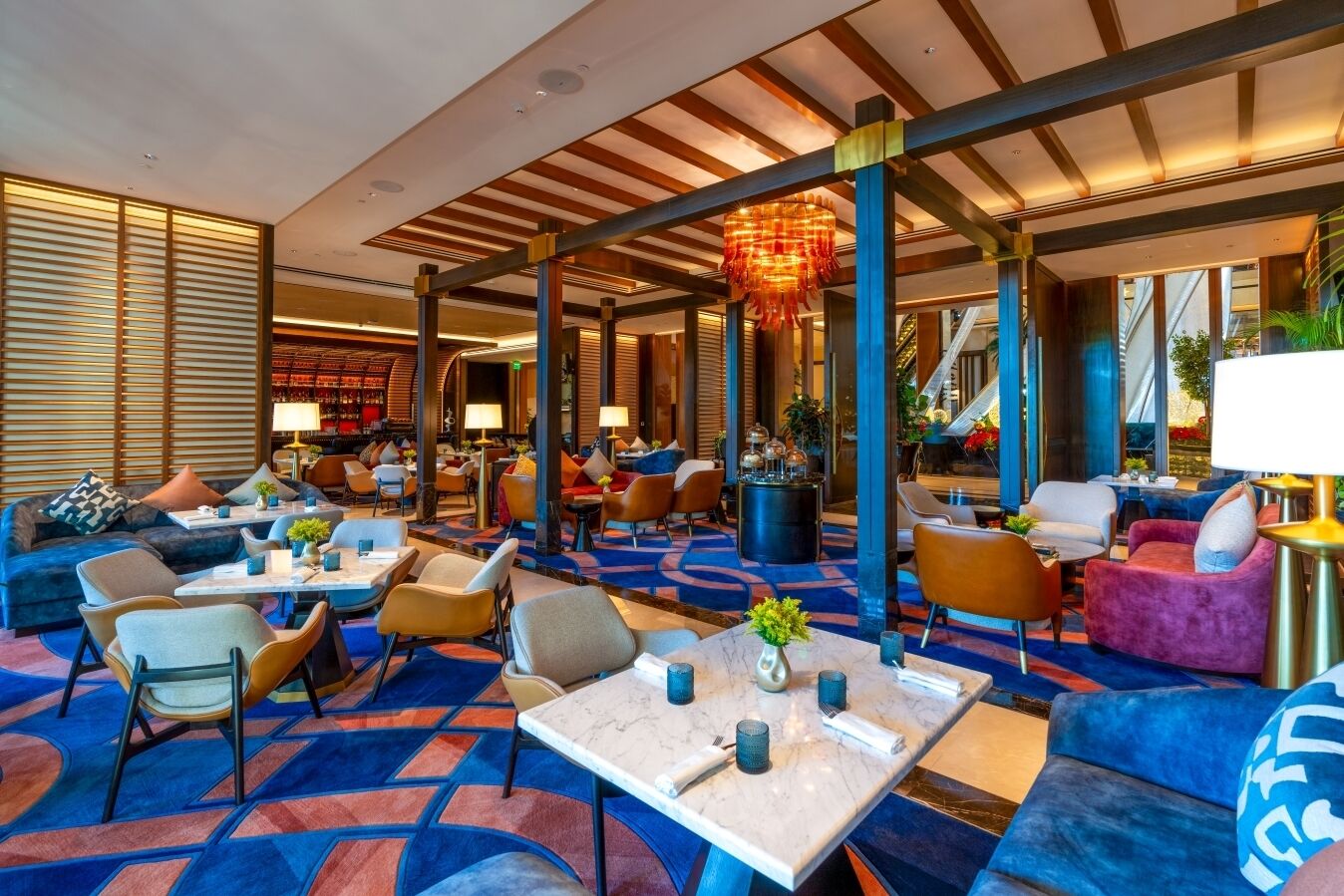 A spacious lobby with a mix of seating areas, including sofas and chairs, and a patterned carpet.