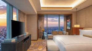 A modern hotel room with a large bed, a flat-screen TV, a sofa, and a view of the cityscape. - Solaire Resort Quezon City – Previously known as Solaire Resort North (Quezon City)
