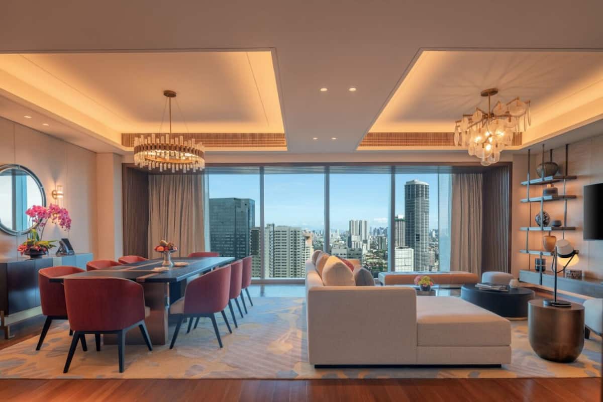 A modern living room with a dining area, large windows with a city view, and contemporary furnishings.