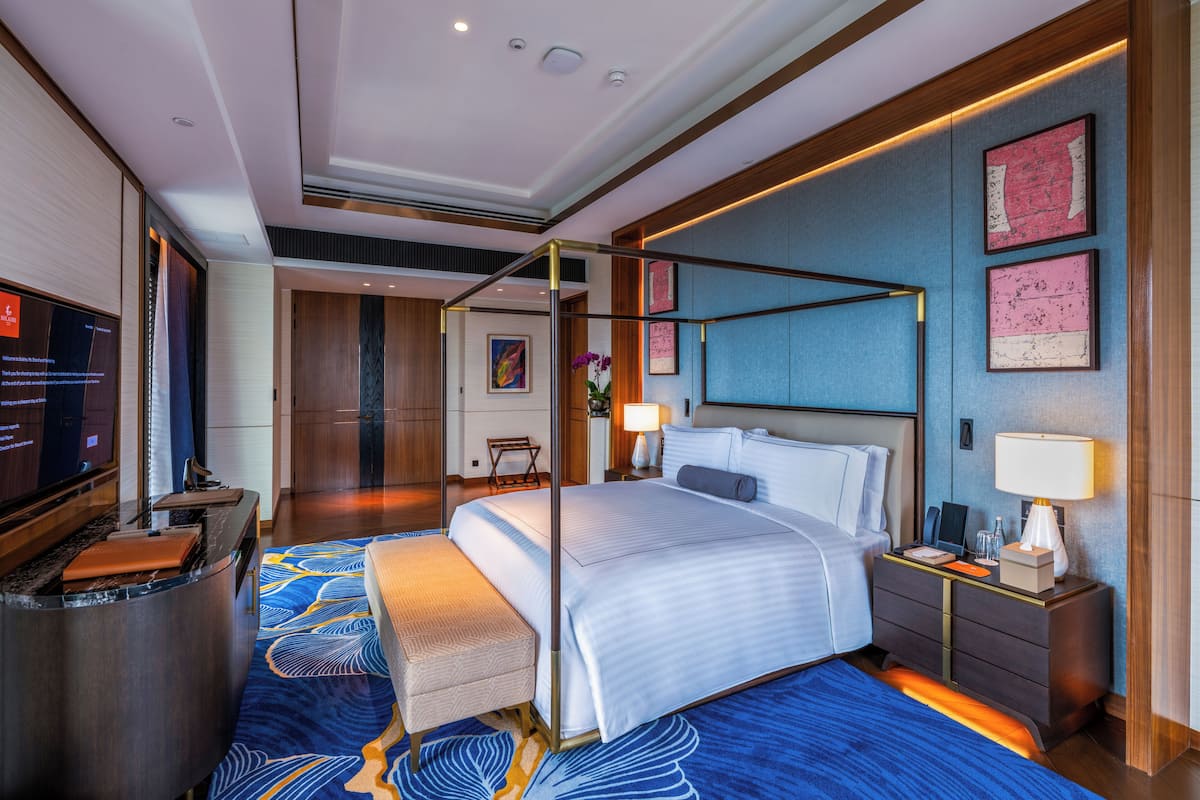 A modern hotel room with a large bed, a desk, and a television.