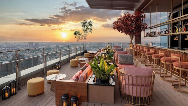 A rooftop bar with seating, a bar area, and a view of the city skyline at sunset. - Solaire Resort Quezon City – Previously known as Solaire Resort North (Quezon City)