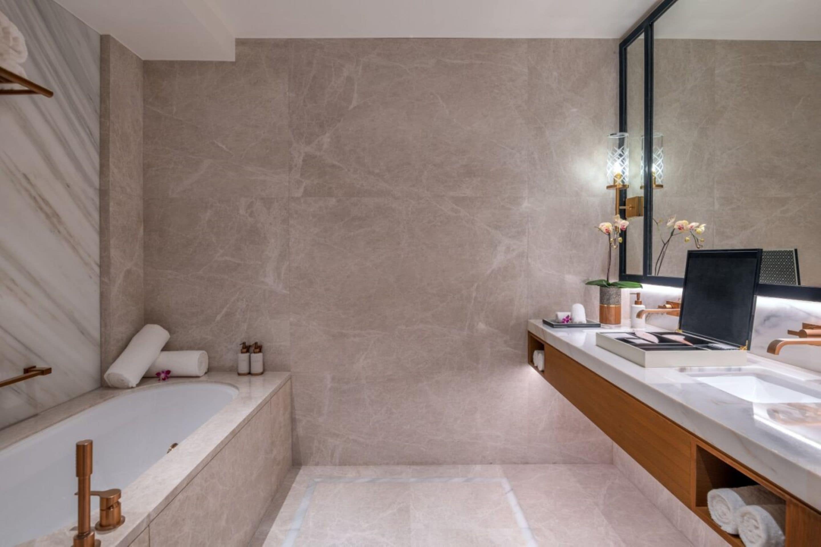 A modern bathroom with a bathtub, a large mirror, and a vanity with a sink.