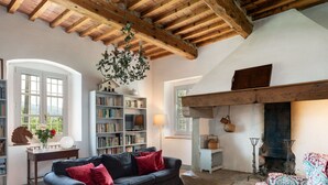 A cozy living room with a black sofa, red cushions, a wooden ceiling, a fireplace, and a bookshelf. - Mirandola by Interhome (Vicchio)