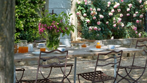 An outdoor dining area with rustic metal chairs and a wooden table set for breakfast. - Mirandola by Interhome (Vicchio)