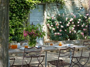 An outdoor dining area with rustic metal chairs and a wooden table set for breakfast. - Mirandola by Interhome (Vicchio)