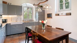 A modern kitchen with grey cabinets, a wooden dining table, and a vase with flowers. - Mirandola by Interhome (Vicchio)