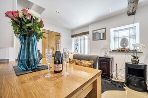 Un salon moderne avec une table basse en bois, un vase rempli de fleurs, une bouteille de champagne et deux verres.