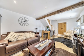 Ein modernes Wohnzimmer mit einem braunen Ledersofa, einem Holztisch und einer großen Wanduhr.