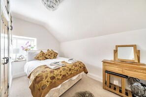 A bedroom with a bed, a wooden dresser, a mirror, and a ceiling fan.