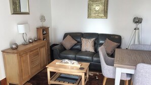 A living room with a leather sofa, wooden coffee table, and a dining area with a table and chairs.