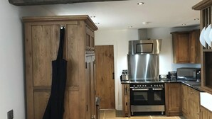 Une cuisine dotée de meubles en bois, d’une hotte en acier inoxydable et d’un four encastré.