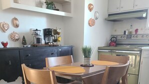 A kitchen with a wooden dining table and chairs, a coffee machine, and a stove.