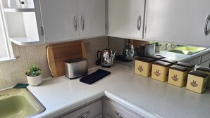 A kitchen with white cabinets, a toaster, a kettle, and a sink.