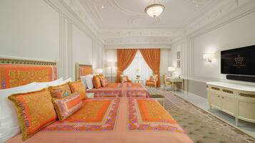 A luxurious bedroom with a large bed, a television, and a desk.