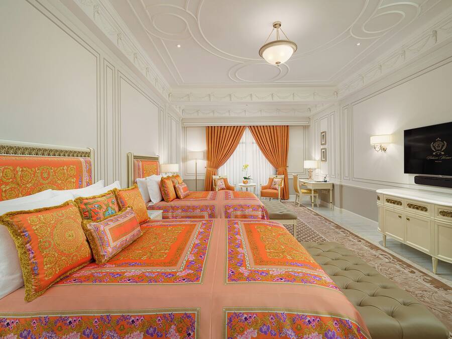 A luxurious bedroom with a large bed, a television, and a desk.