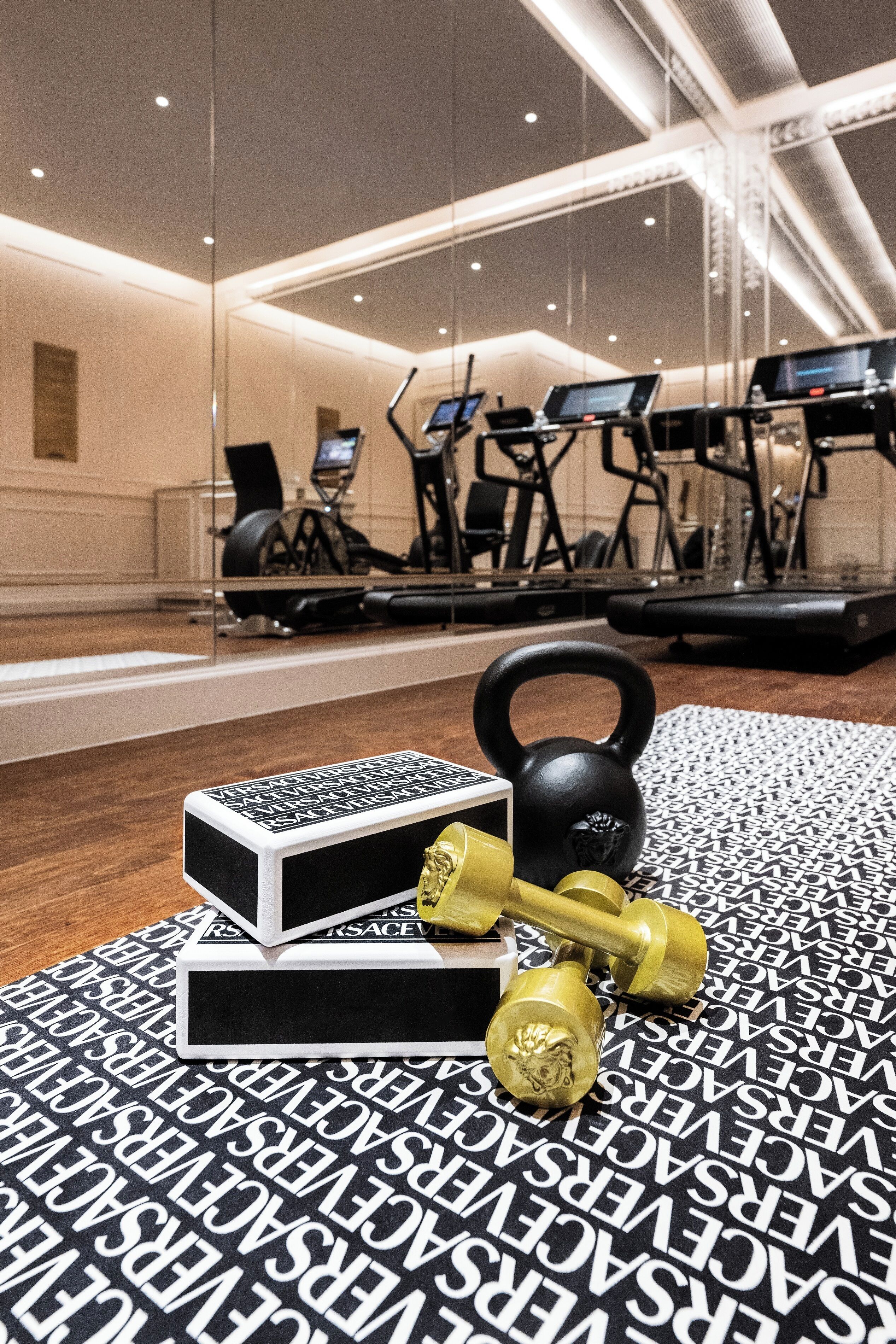 A gym with exercise equipment, a kettlebell, dumbbells, and a mirror reflecting the equipment.