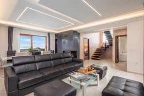 A modern living room with a sectional sofa, a coffee table, and a staircase leading to an upper floor. - Villa Vilani Spa & Pool, Krasica, Croatia (Krasica)