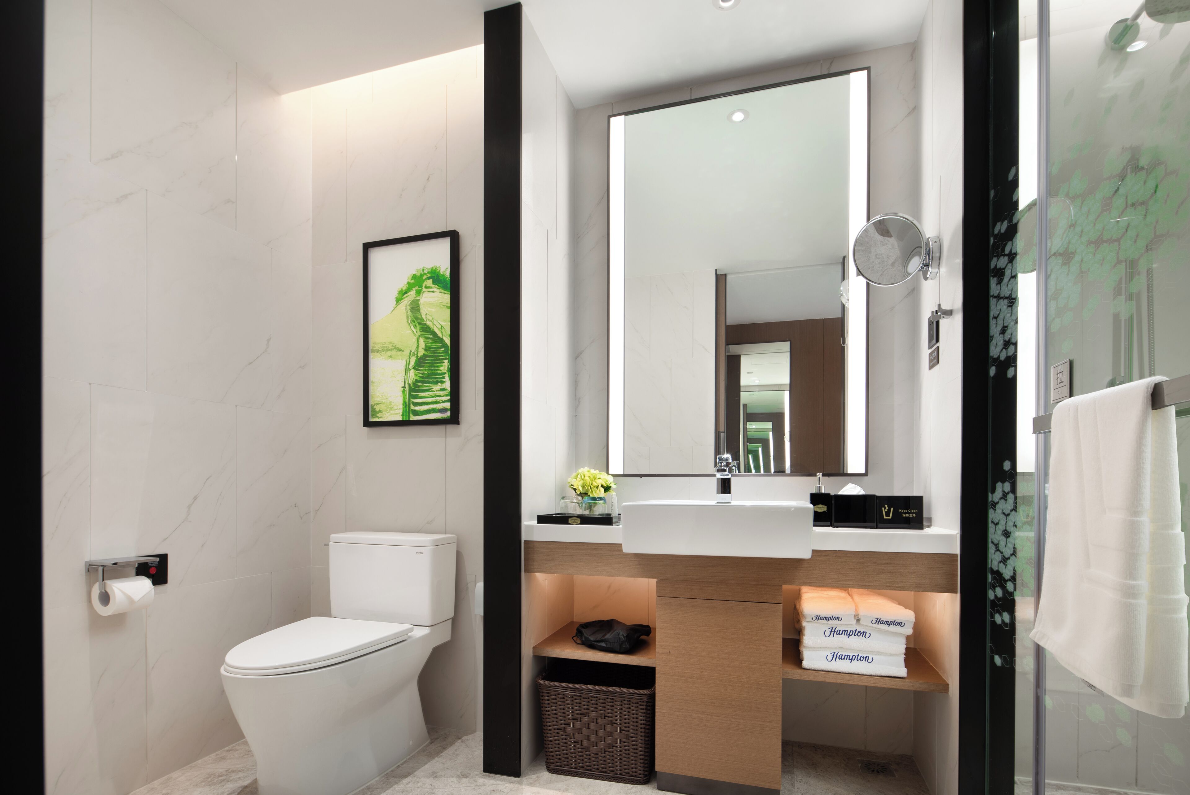A modern bathroom with a toilet, sink, and mirror.