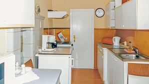 A compact kitchen with a refrigerator, coffee maker, and a clock on the wall.