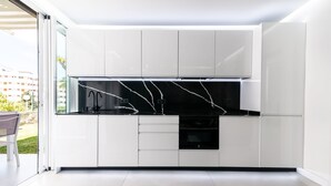 Eine moderne Küche mit weißen Schränken, einer schwarzen Marmor-Spritzschutzleiste und einem eingebauten Backofen.