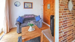 A cozy living room with a grey sofa, blue cushions, a wooden coffee table, and a vase of flowers.