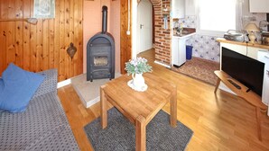 A cozy room with a fireplace, a dining table, and a kitchen area.