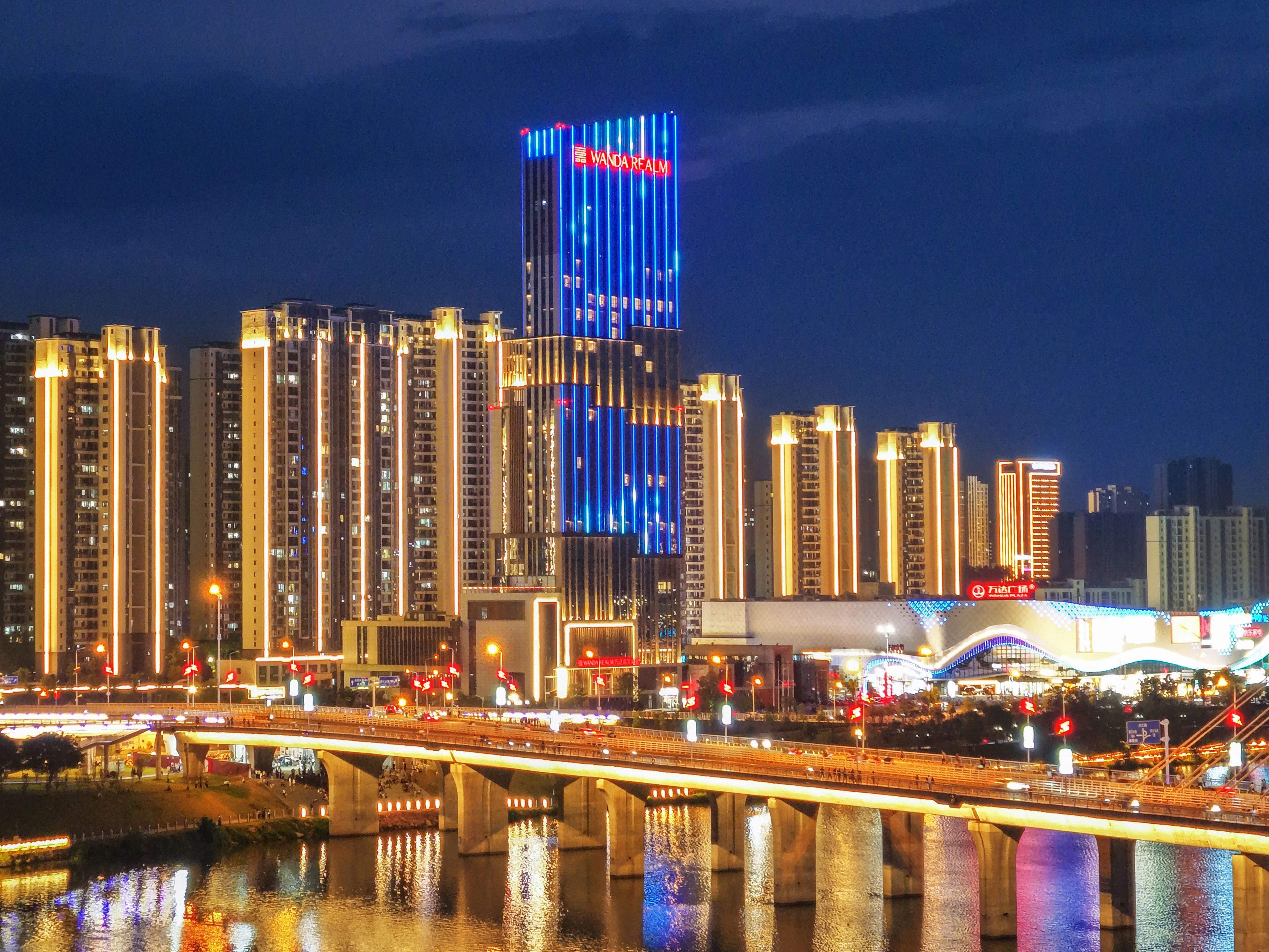 A city skyline with illuminated buildings, a river, and a bridge.