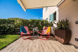 Une terrasse extérieure avec deux chaises rouges, une table et un pot de fleurs.