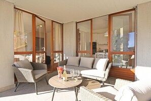 Ein geräumiger Balkon mit Korbmöbeln, einem Esstisch und Blick ins Innere.